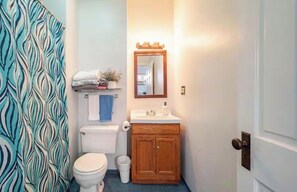 A bathroom with a toilet, sink, wooden cabinet, and a mirror. - Spacious 3-bedroom house in beautiful Chicago with AC (Chicago)