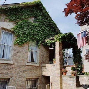 A brick building with a balcony, an American flag, and potted plants. - Spacious 3-bedroom house in beautiful Chicago with AC (Chicago)