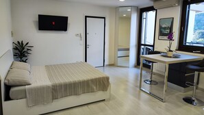 Een moderne slaapkamer met een bed, nachtkastje en een aan de muur bevestigde televisie.