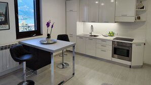 Een moderne keuken met witte kastjes, een roestvrijstalen spoelbak en een oven. Er is een raam met uitzicht op bergen.