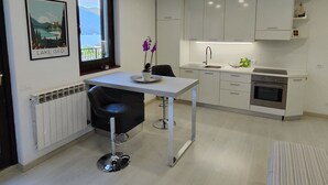 Een moderne keuken met witte kasten, een roestvrijstalen oven, een raam met uitzicht en een barstoel.