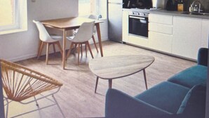 A compact kitchen with a dining area, a sofa, and a hanging light fixture. - Ideal stay in Le Croisic (Le Croisic)