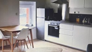 A compact kitchen with a dining table and chairs, a stove, and a refrigerator. - Ideal stay in Le Croisic (Le Croisic)