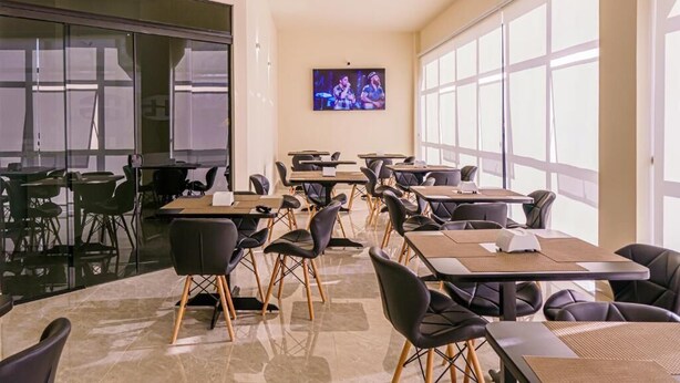 Une salle de conférence équipée de tables et de chaises, d’un écran de télévision et de grandes fenêtres.