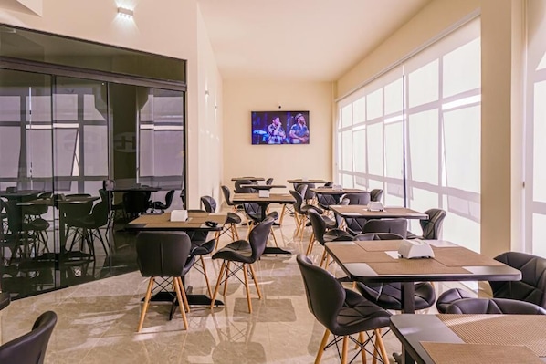 A conference room with tables and chairs, a television screen, and large windows.