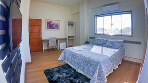 Une chambre à coucher avec un lit, un bureau, une chaise, une fenêtre et une porte.