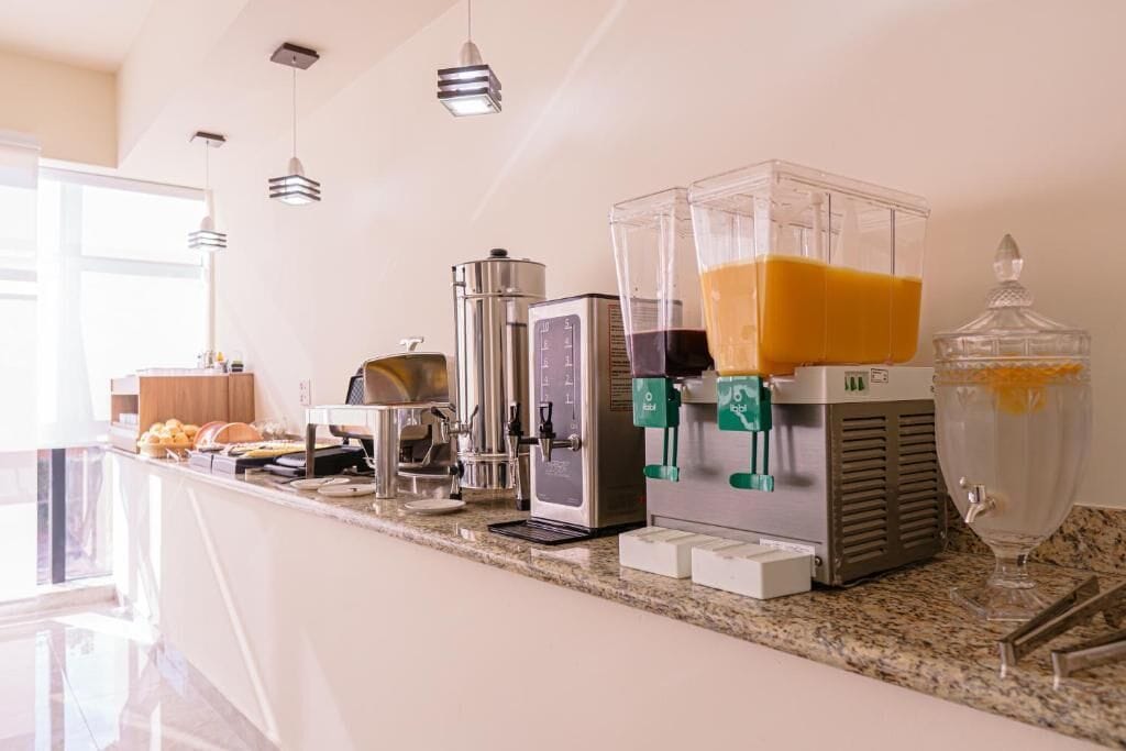 Une cuisine moderne équipée d’une machine à café, d’un mixeur et d’un récipient en verre contenant du jus d’orange.