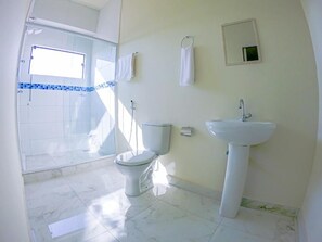 Une salle de bain comprenant des toilettes, un lavabo et un espace douche.