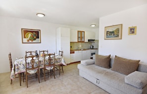 A dining area with a table and chairs, a sofa, and a kitchen in the background. - Peaceful Stay With bbq and Parking (Umag)