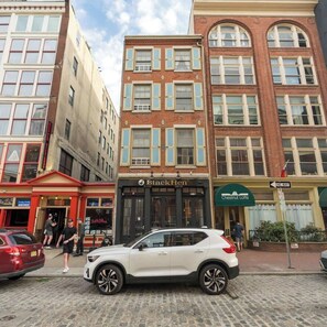 A street view with a white SUV parked in front of a building with a sign reading 'Black Hen.' - Cozy Center City Studio | By Rafa Properties (Philadelphia)