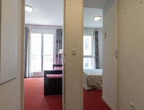 Ein Zimmer mit einem Bett, einem Schreibtisch und einem Vorhangfenster.