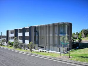 Un bâtiment moderne à la façade incurvée, doté de nombreux balcons et d’une pelouse bien entretenue.