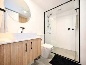 Une salle de bain moderne avec un meuble-lavabo en bois, des toilettes blanches et une cabine de douche en verre.