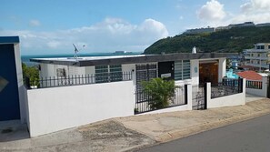 Ein modernes Gebäude mit flachem Dach, einem kleinen Balkon und einem Tor.