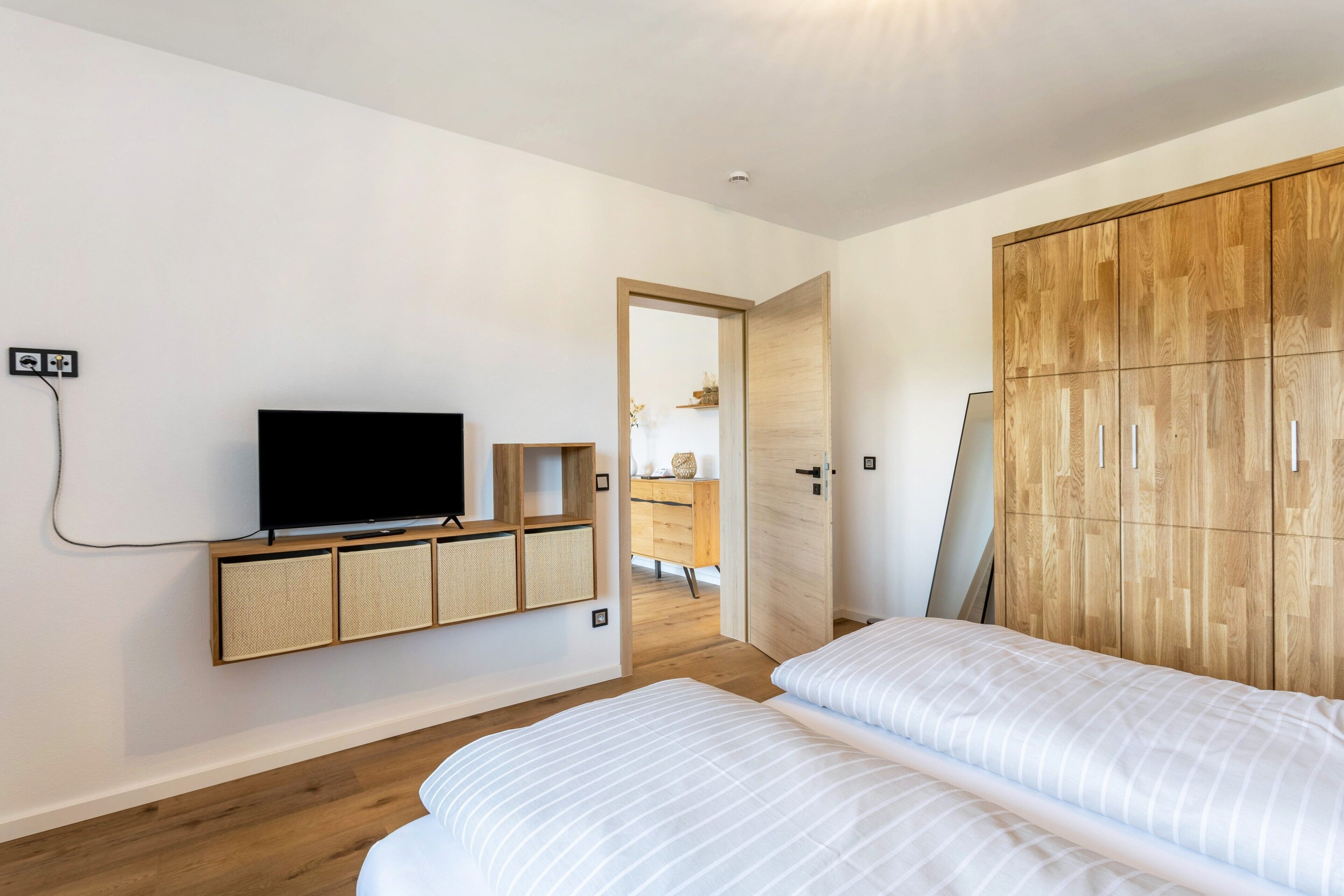 Un dormitorio con televisión, armario de madera y cama.