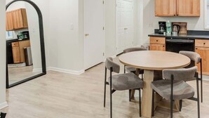A modern kitchen with wooden cabinets, a round dining table with chairs, and a pendant light. - Cozy & Convenient 3-Bedroom Near Washington Square (Philadelphia)