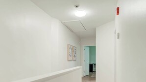 A hallway with white walls, a light wooden floor, and a ceiling light. There is a door at the end of the hallway. - Cozy & Convenient 3-Bedroom Near Washington Square (Philadelphia)