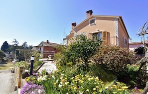 A two-story house with a garden in front, a clear sky, and a visible street. - Quiet Retreat With Terrace (Umag)