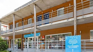 Ein Hotel mit Empfangsbereich, Holzfassade und einem Schild mit den Aufschriften 'Vacanzele' und 'RÉCEPTION'.