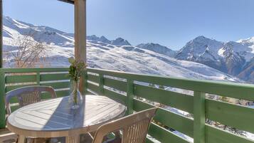 A table with chairs and a vase of flowers on a balcony with a mountain view.