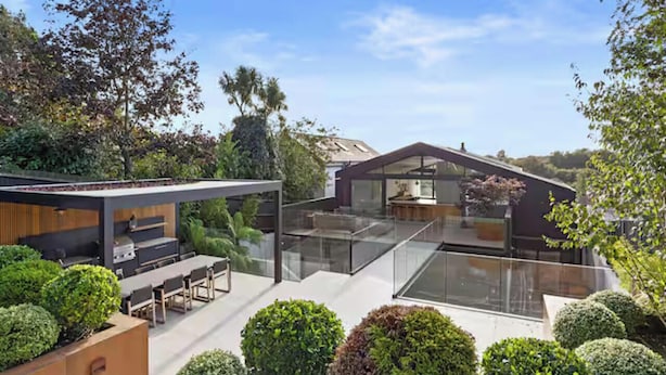 Een modern huis met een glazen patio, een eethoek en een keuken.