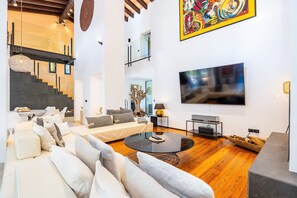 Ein modernes Wohnzimmer mit einer Sofagarnitur, einem Couchtisch, einem Fernseher und einer Treppe.