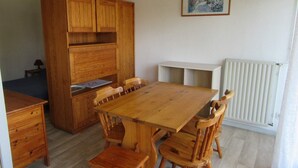 Une table à manger en bois, avec six chaises, un buffet en bois et un radiateur fixé au mur.