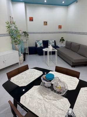 Uma sala de estar moderna com área de jantar, sofá, mesa de centro e um armário.