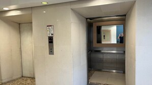 Un ascensor con pantalla digital, espejo y piso de baldosas.