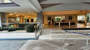 Un vestíbulo espacioso con una recepción, una escalera y un pequeño jardín.