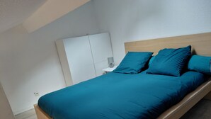 Un dormitorio con cama, mesita de noche, unidad de almacenamiento en la pared y suelo de madera.