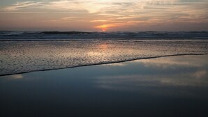 Una playa al atardecer con olas y cielo despejado.