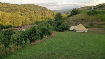 Una carpa en un campo cubierto de pasto, con colinas al fondo.