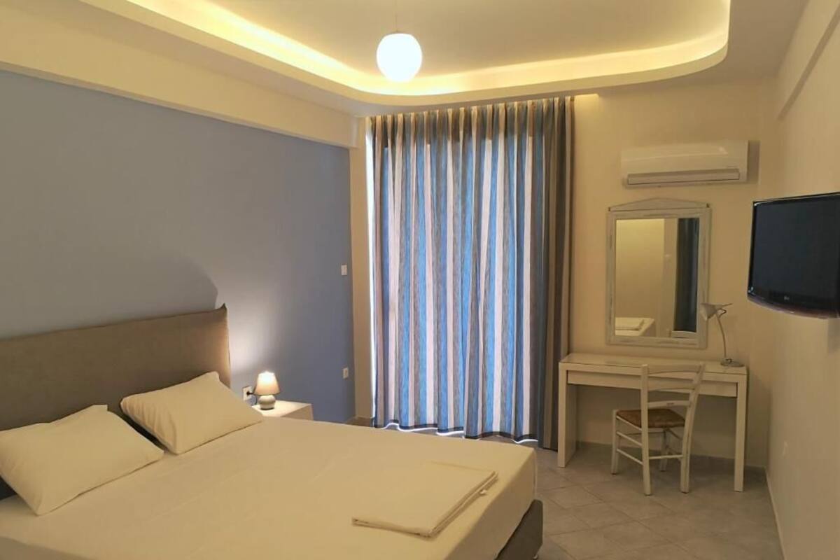 Et hotelværelse med en seng, et natbord, lampe, skrivebord, stol og et fjernsyn.