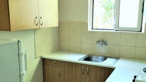 A kitchen with wooden cabinets, a white countertop, a sink, and a window.