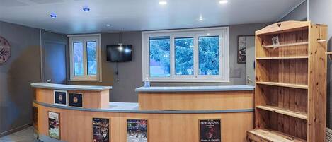 A reception desk with a television, posters, and a wooden shelf unit.