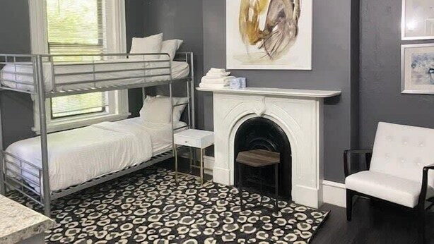 A room with a bunk bed, a fireplace, a white chair, and a leopard print rug. - Perfect For Solo Travelers Or Friends! (Boston)