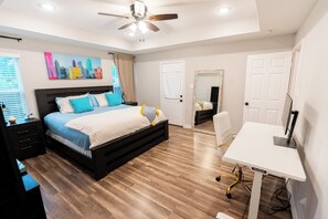 Ein Schlafzimmer mit Bett, Schreibtisch und Deckenventilator.
