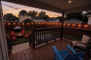 Eine überdachte Terrasse mit Feuerstelle, Sitzgelegenheiten im Freien und Blick auf den Garten.