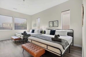A bedroom with two beds, a bench, and a window with blinds. - Level Up Vegas Desert Game House Stay! (North Las Vegas)