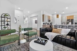 A modern living room with a green sofa, a black leather couch, and a white coffee table.