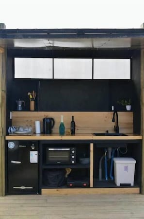 A compact kitchenette with a microwave, coffee maker, and a small refrigerator.