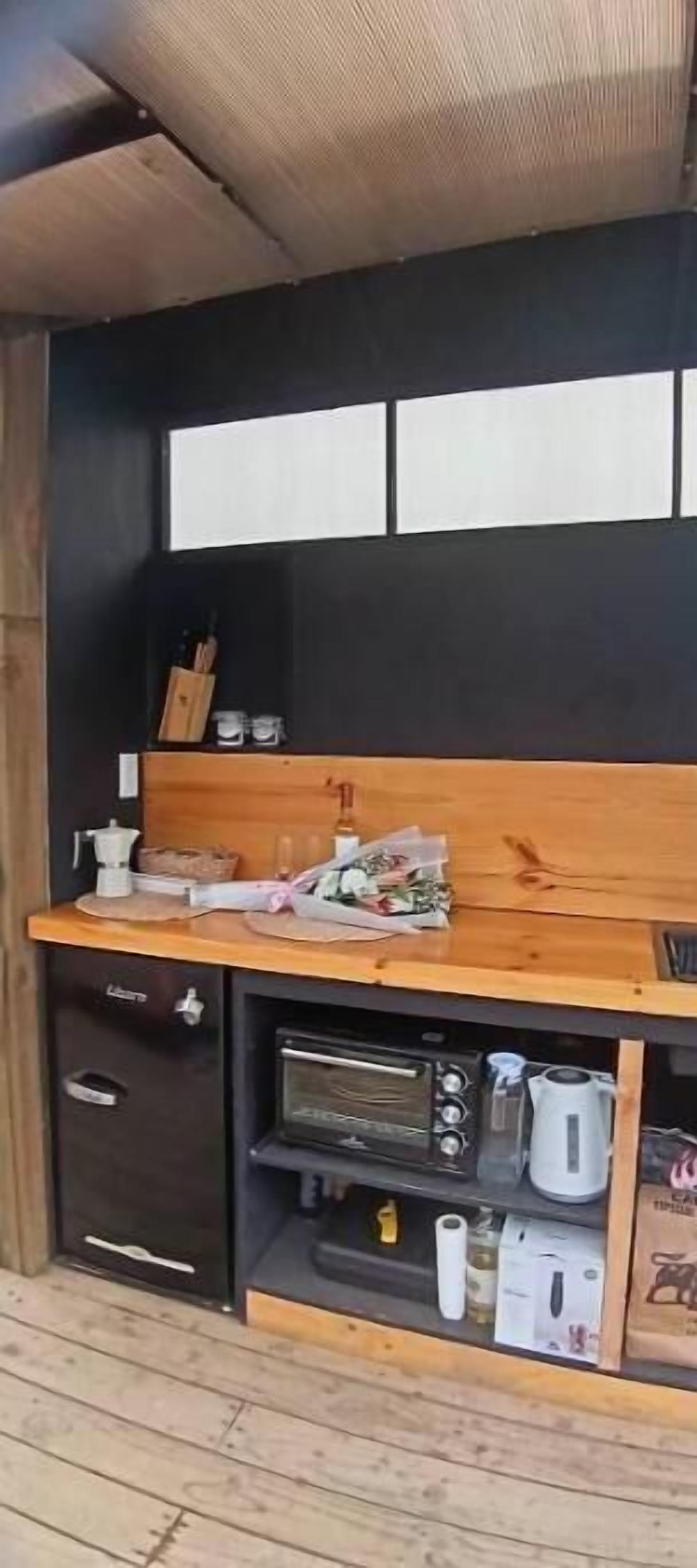 Una cocina compacta con encimera de madera, horno empotrado y microondas.