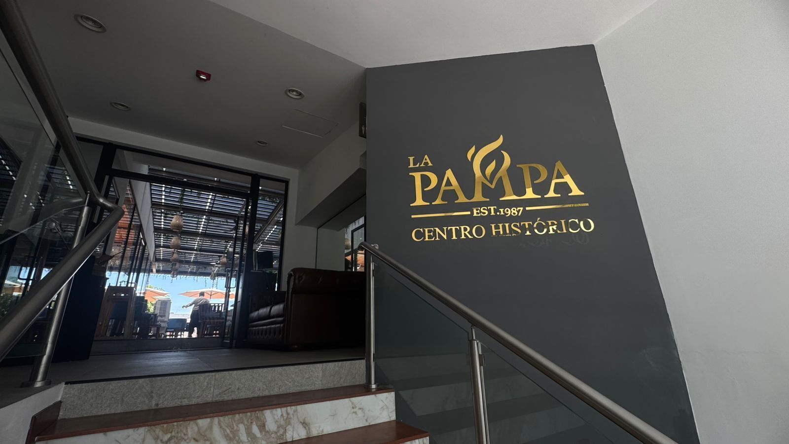Una escala condueix a un restaurant amb un cartell que diu 'La Pampa Centro Histórico'.