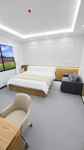 Habitación de hotel moderna con una cama grande, un escritorio, una silla y vistas al exterior.