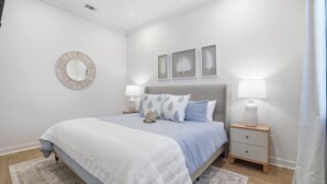 Un dormitorio con cama, mesitas de noche, un espejo y decoración en la pared.