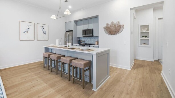 Una cocina moderna con una isla central, taburetes de bar y una lámpara colgante.