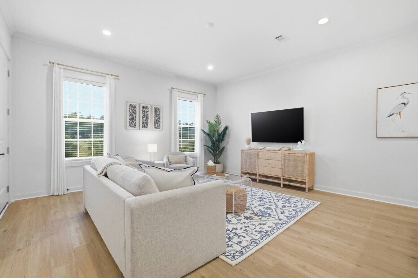 A spacious living room with a sofa, a TV, and a large window.