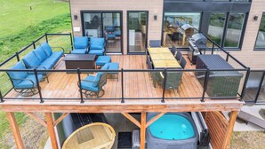Et moderne hus med terrasse, udendørs møbler, et spabad og grillområde.
