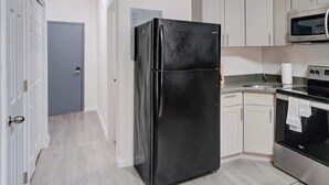 Une cuisine moderne avec un réfrigérateur noir, un four à micro-ondes en acier inoxydable et un four traditionnel.